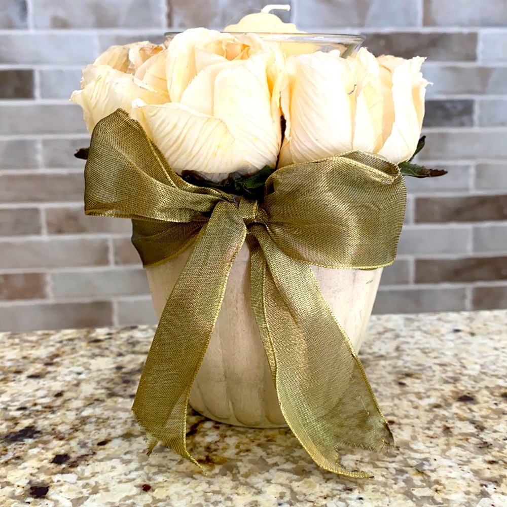 Candle holder adorned in a circle of flowers and bow tie.